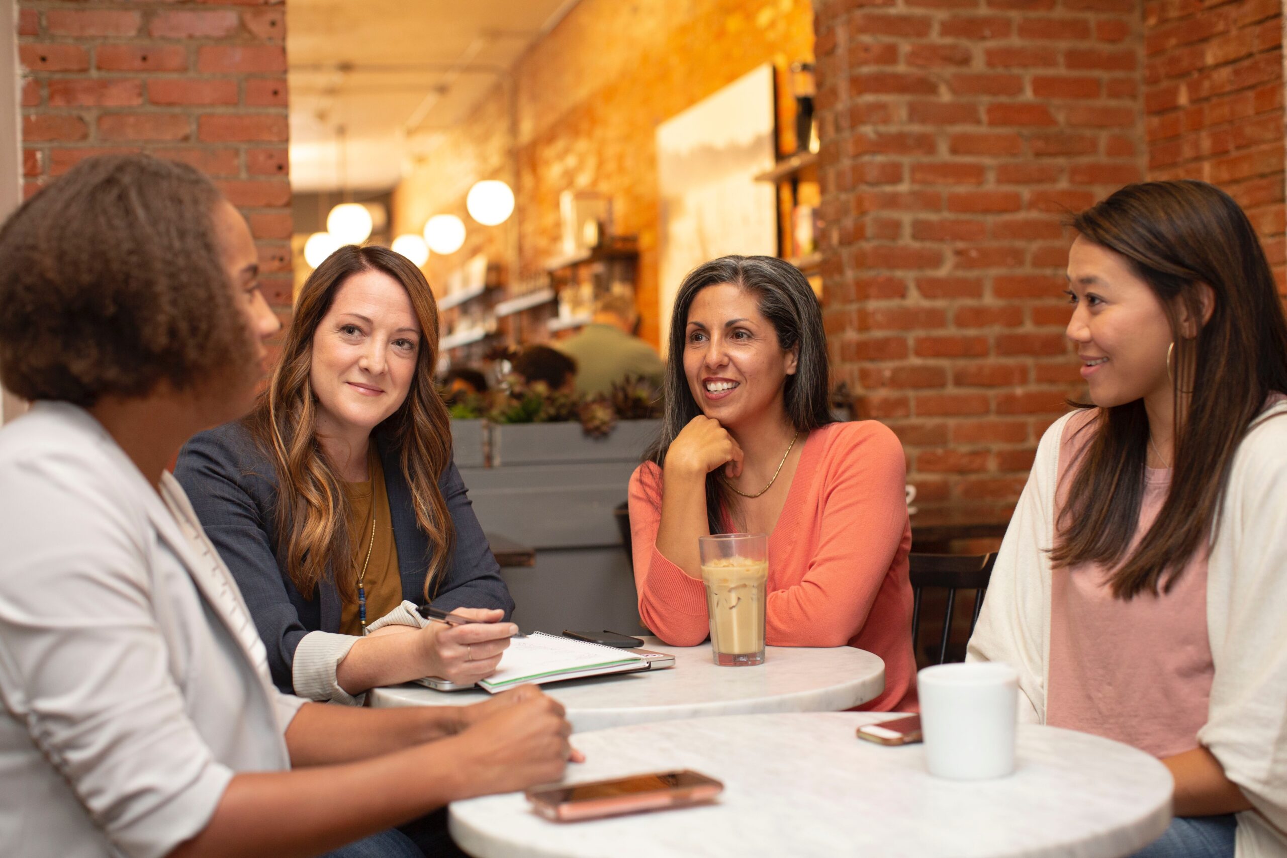 4 women around the table with coffee communicating